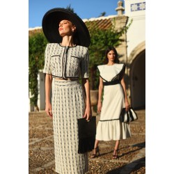 Dos mujeres posando, una con un traje de camisa y falda y otra con vestido